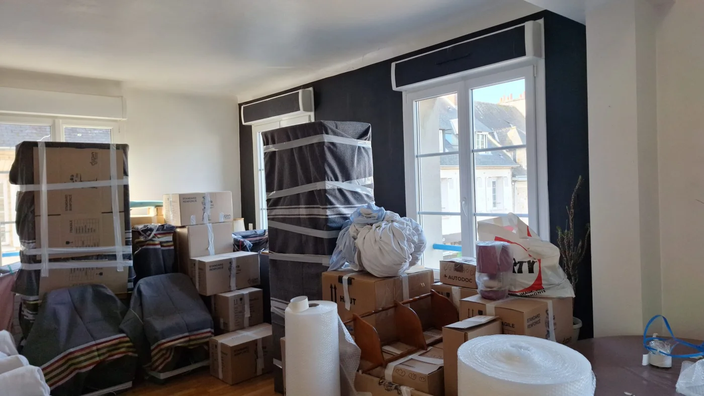 Meubles enveloppés et cartons rassemblés avant le transport à Carpiquet